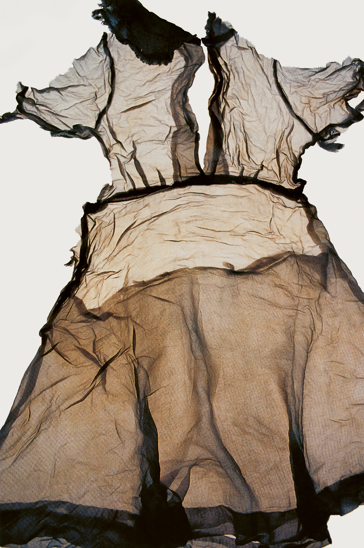 Photograph of fabric hanging on a clothesline, wrinkled and deteriorating, showing the effects of time and weather.