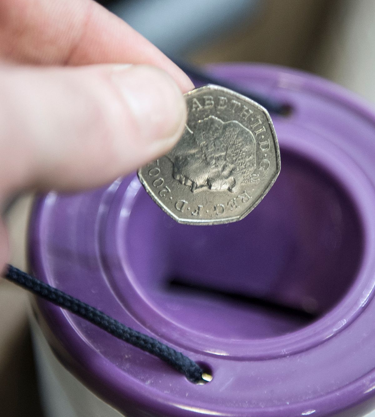 Stock image of a coin being placed in a charity collection