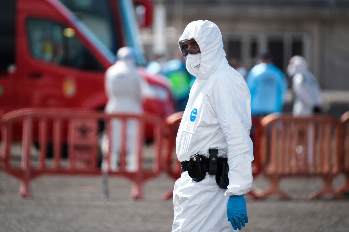 An officer wearing protective gear as passengers leave the MV Hondius cruise ship