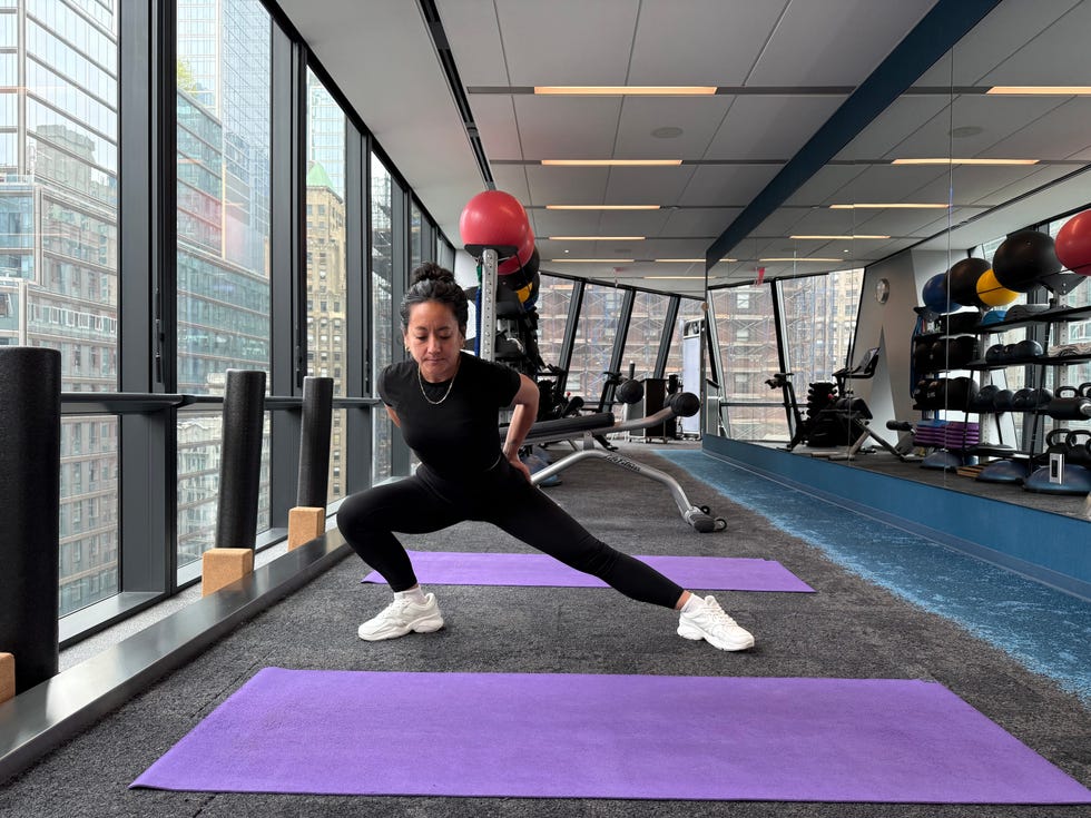 Person performing a lunge in a gym with a city view.