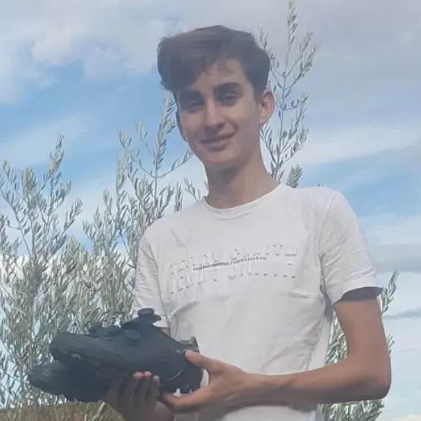French cyclist Paul Seixas holding a pair of cycling shoes.