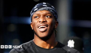 KSI smiles while wearing a black bandana and t-shirt
