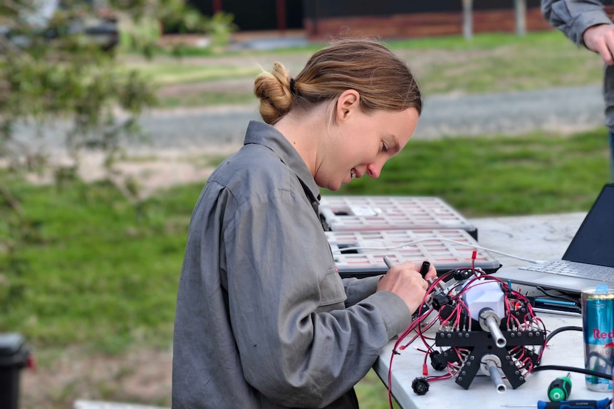 A young woman working on a component of a small rocket