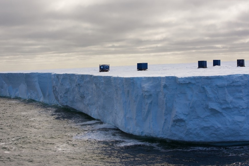 Shipping containers sitting on a massive iceberg.