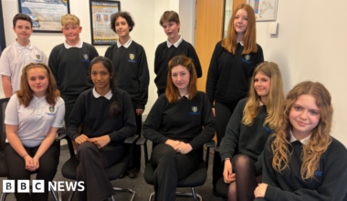 Ten teenagers in school uniform with five sitting down and five standing behind them