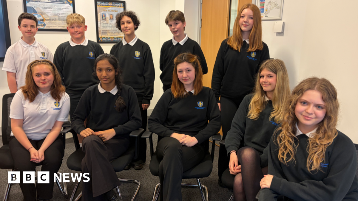 Ten teenagers in school uniform with five sitting down and five standing behind them