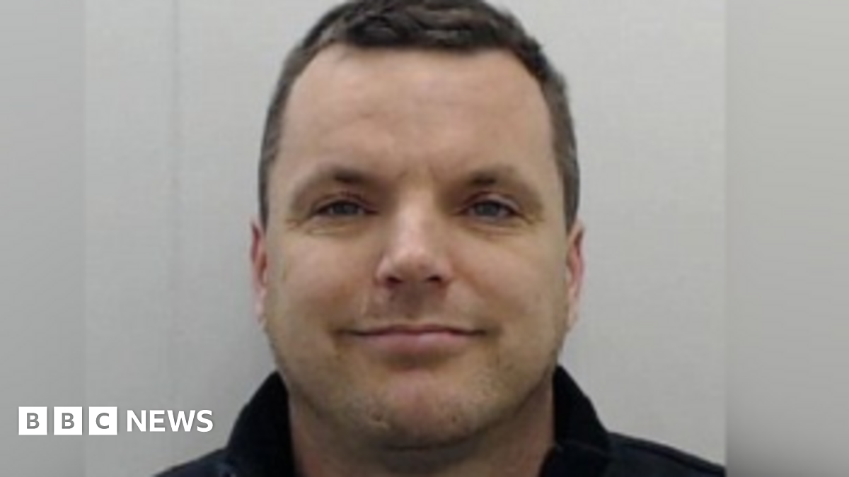 Man smiles at camera in mugshot.