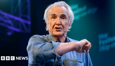 Larry Lamb in a blue shirt gesticulating towards the audience while on stage at Hay