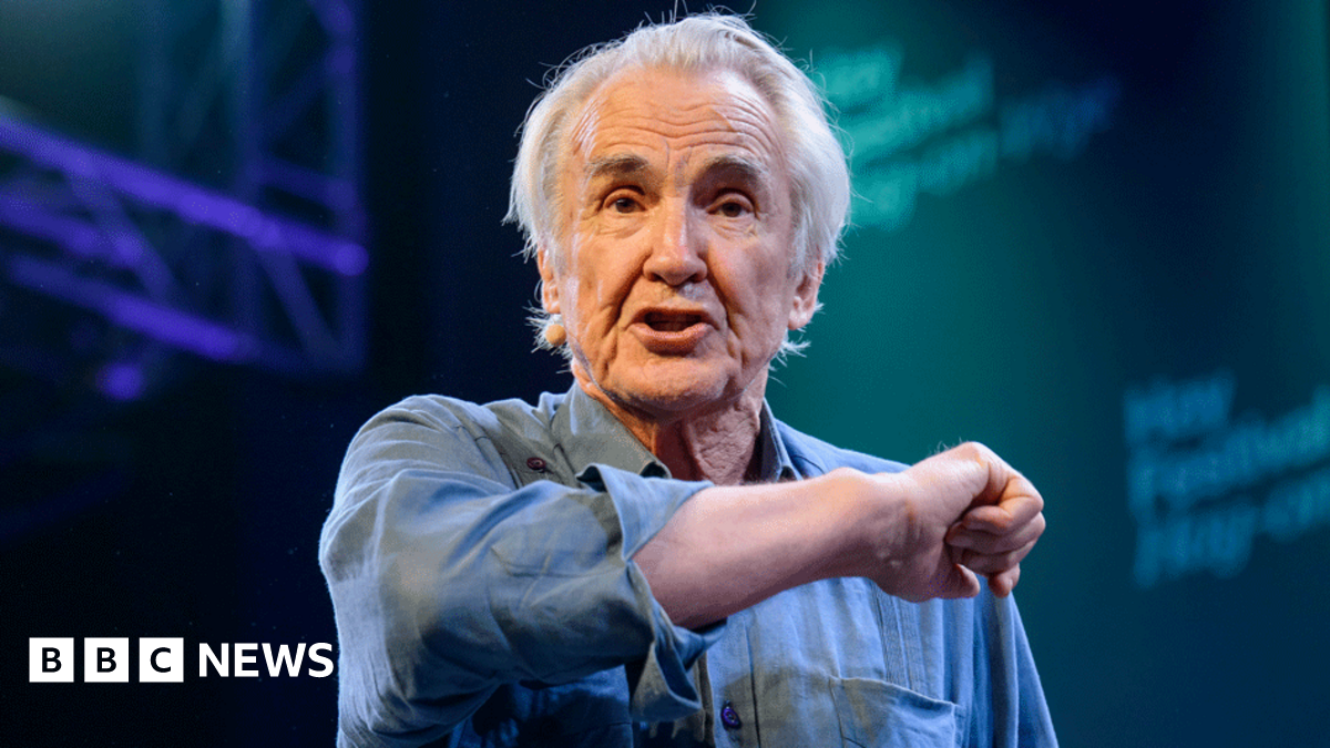 Larry Lamb in a blue shirt gesticulating towards the audience while on stage at Hay