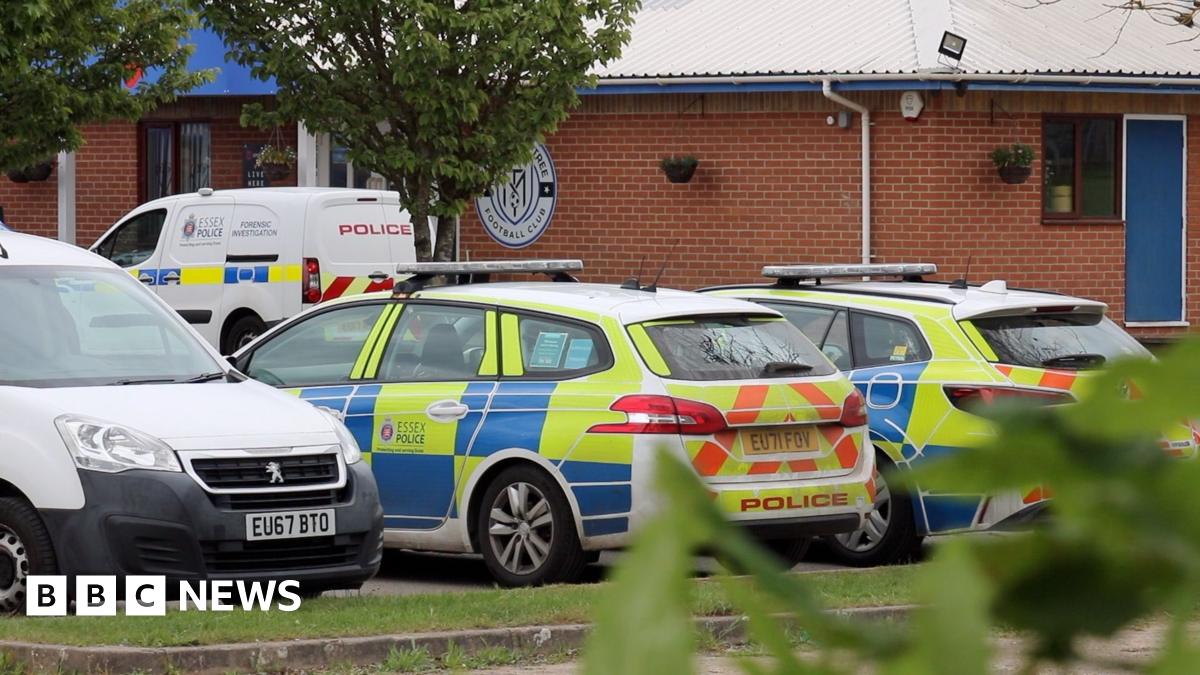 Police cars and vans parked outside Maldon and Tiptree FC's brick clubhouse.