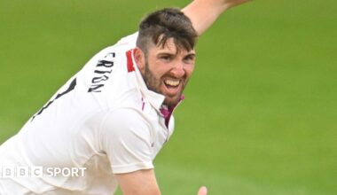 Craig Overton in cricket whites bowls with a grimace
