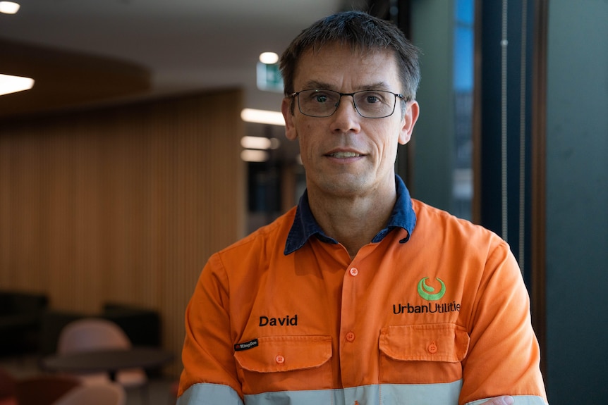 A man wearing a hi-vis orange shirt with an Urban Utilities logo