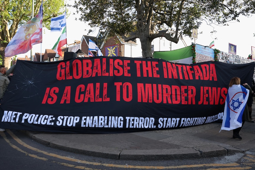 Demonstrators carry a banner saying "globalise the intifdada is a call to murder jews".