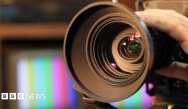 Close-up shot of professional video camera, with its lens zooming in.