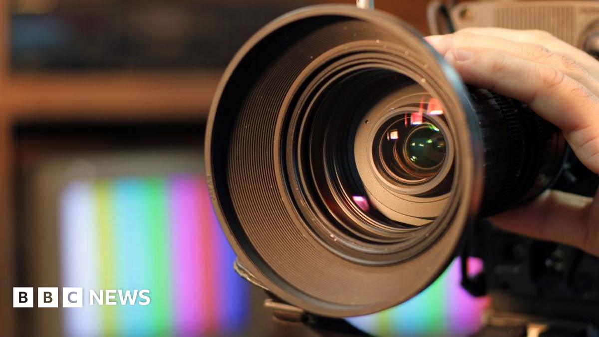 Close-up shot of professional video camera, with its lens zooming in.