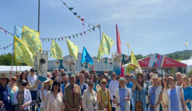 A large group of people, some dressed in river costumes, stand outside the Hay Festival entrance