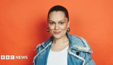 Jessie J with her hair tied back, big silver hoop earrings and a denim jacket and white top