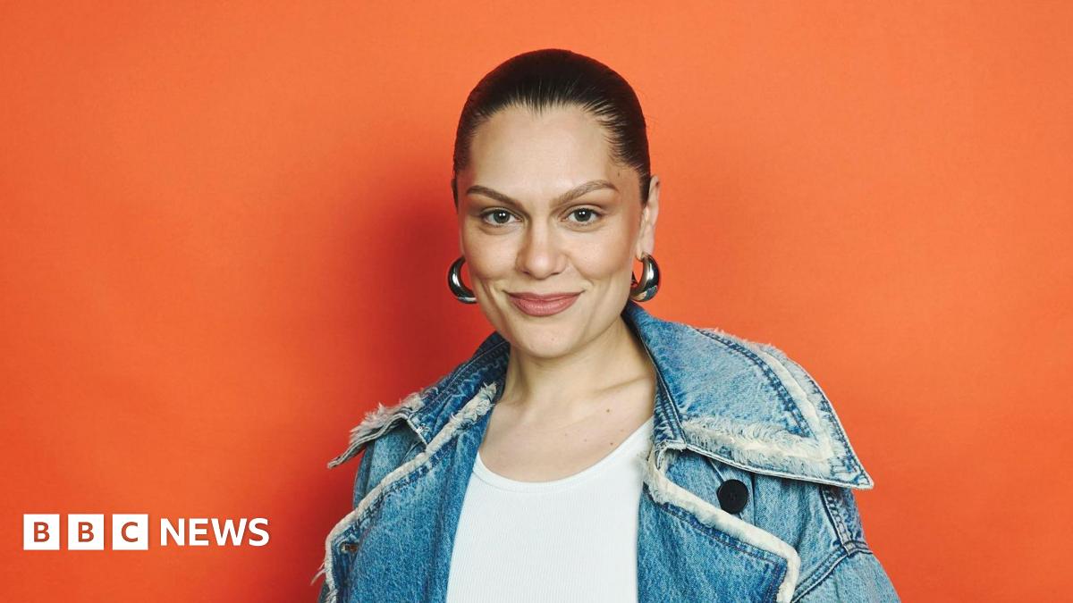 Jessie J with her hair tied back, big silver hoop earrings and a denim jacket and white top