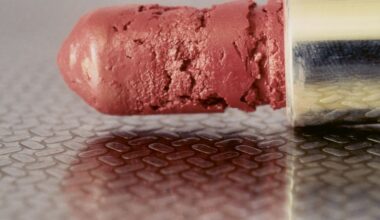 Detailed photograph of a pink lipstick on textured surface with visible cracks and wear indicating age and use.