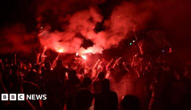 PSG supporters release flares during clashes with police in Paris.