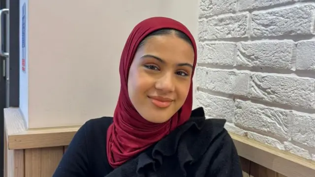 Zaynah wearing a burgandy headscarf and black top