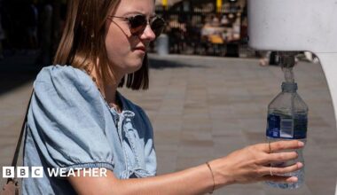 People using a water fountain to top up their water bottles in the Spring heat to keep cool and hydrated during the first heatwave of the year