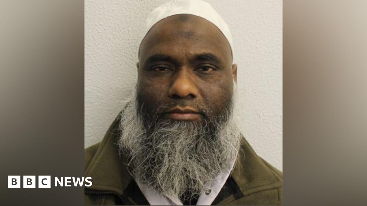 A man with a long grey beard looks at the camera