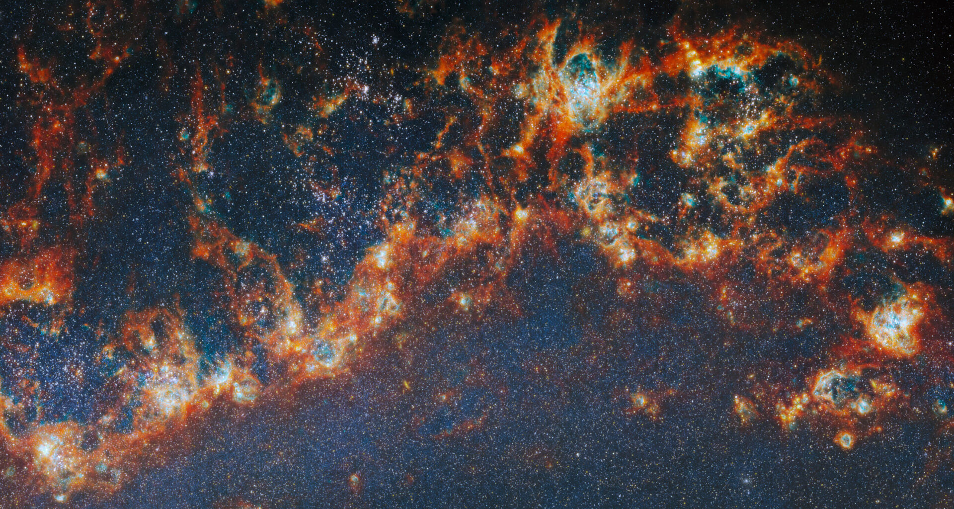 A large, long portion of one of the spiral arms in galaxy M51. Red-orange, clumpy filaments of gas and dust that stretch in a chain from left to right comprise the arm. Shining cyan bubbles light up parts of the gas clouds from within, and gaps expose bright star clusters in these bubbles as glowing white dots. The whole image is dotted with small stars. A faint blue glow around the arm colors the otherwise dark background.
