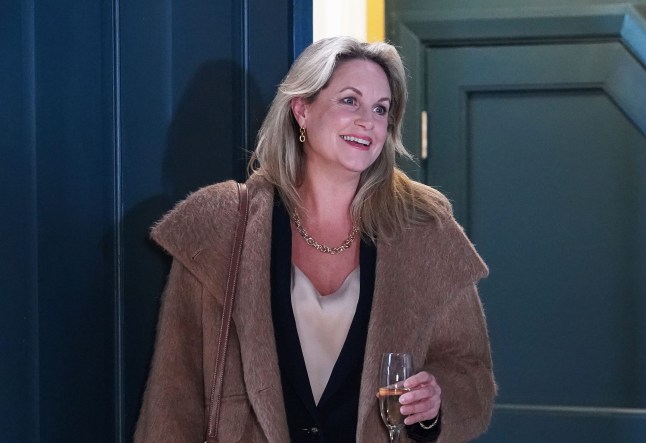 Sam Mitchell smiling and holding a champagne glass in EastEnders.