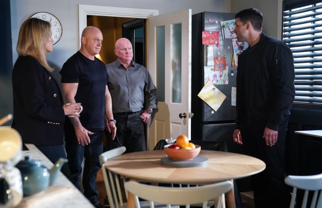 Sam, Phil and Grant Mitchell facing off with Mark Fowler in the kitchen in EastEnders