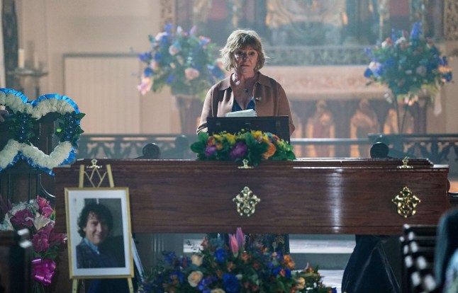 Julie stands beside Nigel's coffin in the church in EastEnders