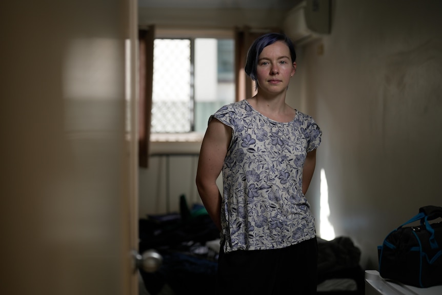 A woman standing behind bags in a room.