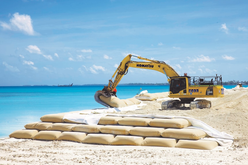Bags of sand are picked up and arranged at a Funafuti land reclamation project.