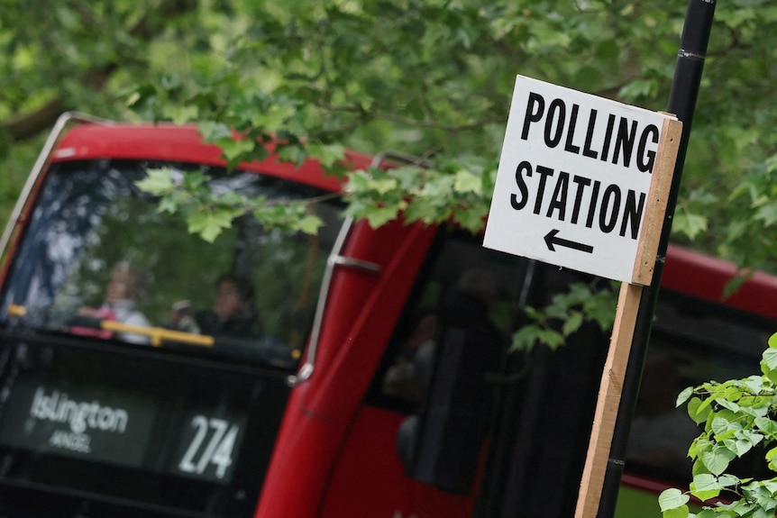 A sign saying "polling station" is visible in front of a red bus.