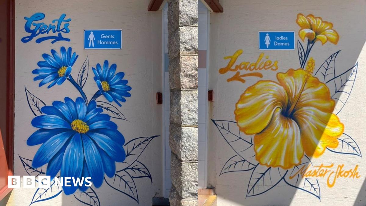 Close-up of two painted walls by public toilets side by side. The left door is labelled “Gents Hommes” and decorated with large blue flowers; the right door is labelled “Ladies Dames” and decorated with large yellow flowers. The artwork is painted directly onto the wall.