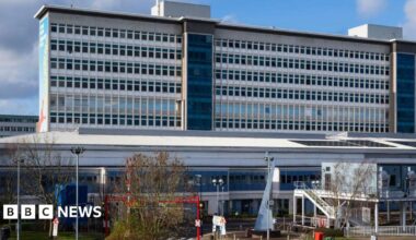 University Hospital Wales main building seen from the front outside. A large high-rise rectangular building rises up behind and a two-storey building is visible in front
