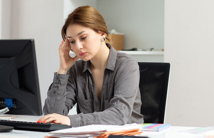 Woman thinking at computer about AI usage and work challenges Woman thinking at computer about AI usage and work challenges