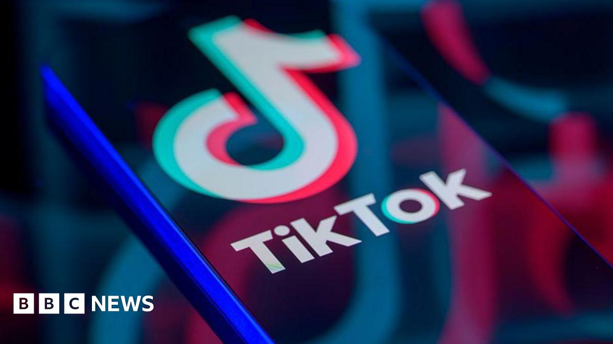TikTok logo displayed on a smartphone screen, with enlarged, faded versions of the logo reflected across it.