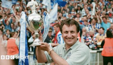Neil Warnock holds up the play-off trophy at Wembley adorned with blue and white ribbons