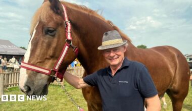 Martin Clunes is standing next to a horse wearing a hat and T-shirt.