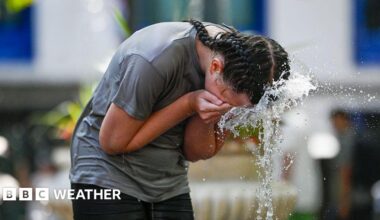 woman spashing water from a fountain on her face to cool down