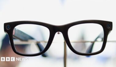 A woman wearing glasses sat on a bench.