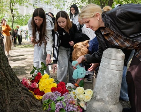People lay flowers in front of a house heavily damaged after a Russian strike on residential neighbourhood in Kyiv, Ukraine.
