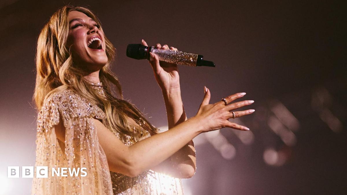 Delta Goodrem waves an Australian flag in celebration as she is voted into the Eurovision Grand Final