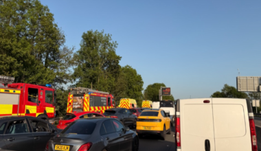 A queue of cars and vans on a motorway with a number of fire engines on the left hand side