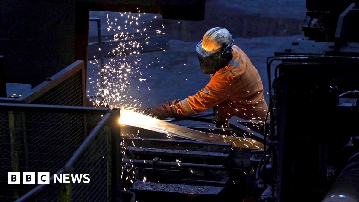 A steelworker wearing orange protective gear welds as sparks flies against a dark background in Scunthorpe Steel works in 2025.