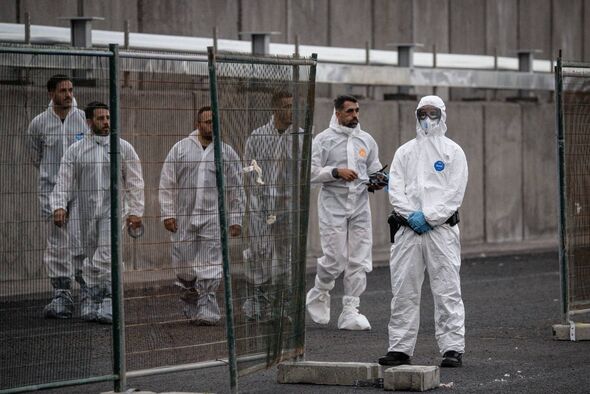 A group of individuals dressed in full protective gear, including white coveralls, masks, and gloves, are standing behind a glas A group of individuals dressed in full protective gear, including white coveralls, masks, and gloves, are standing behind a glas