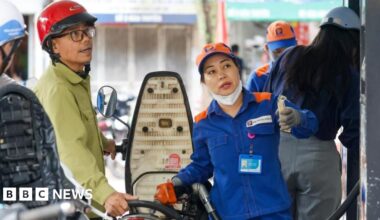 An employee pumps fuel into a customer's motorbike at a petrol station in Hanoi, Vietnam