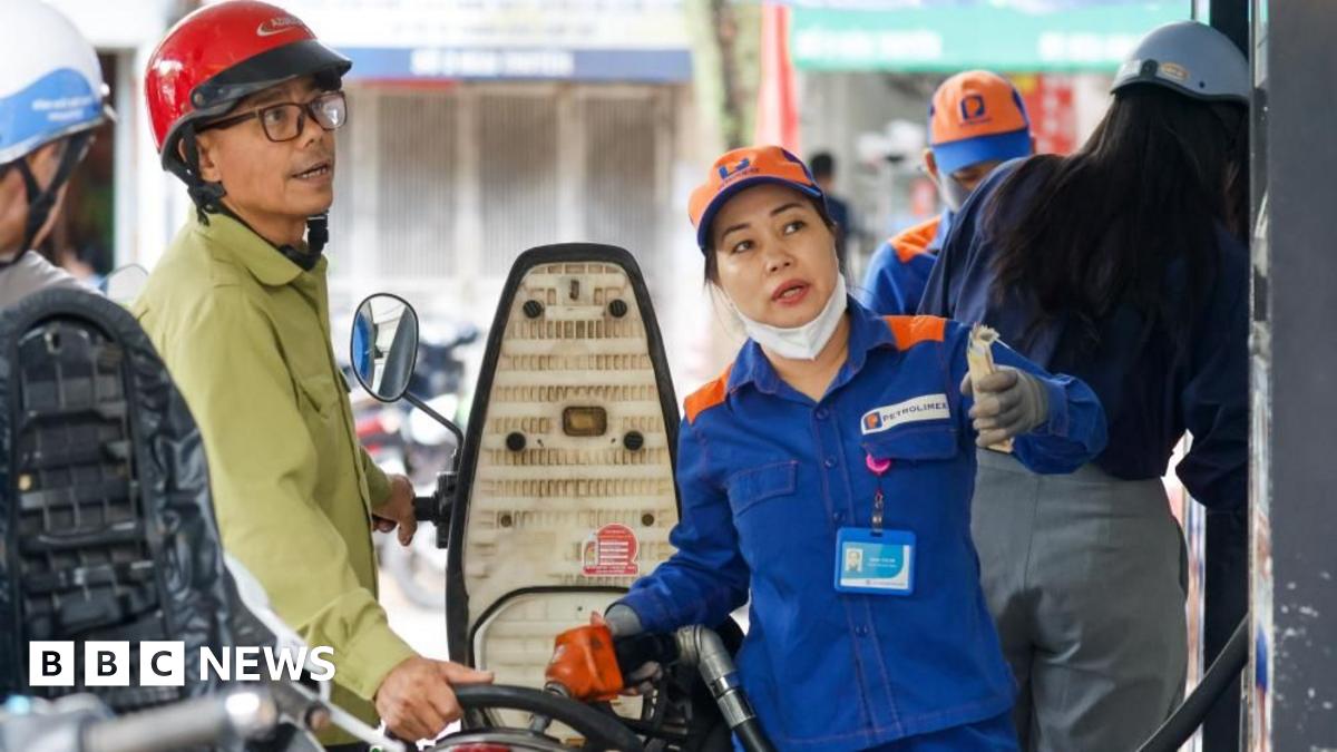 An employee pumps fuel into a customer's motorbike at a petrol station in Hanoi, Vietnam