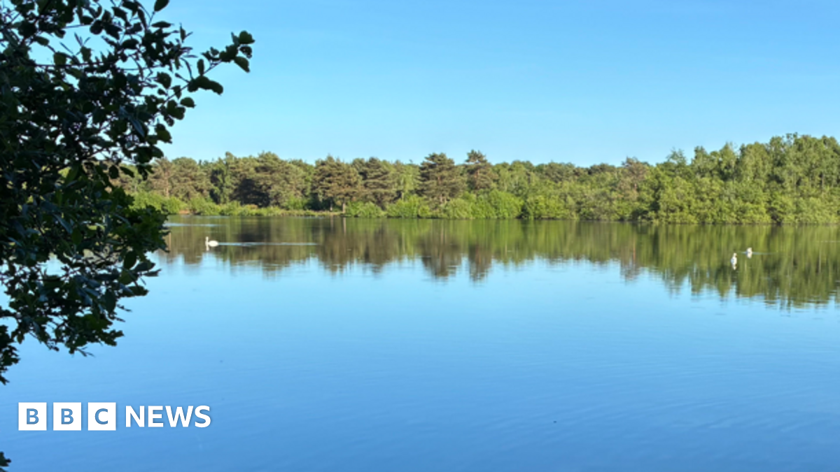 A serene, calm lake under a blue sky